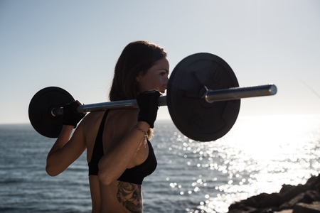 Fitness woman with tattoos lifting weights - Outdoorの写真素材