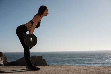 Fitness woman with tattoos lifting weights - Outdoorの写真素材