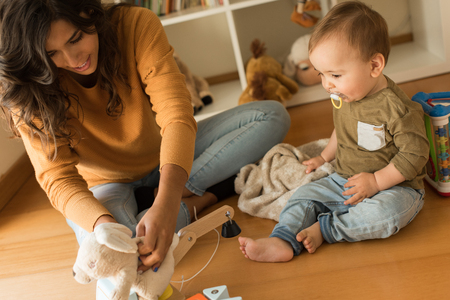 Young Mother playing with toddler at home の写真素材
