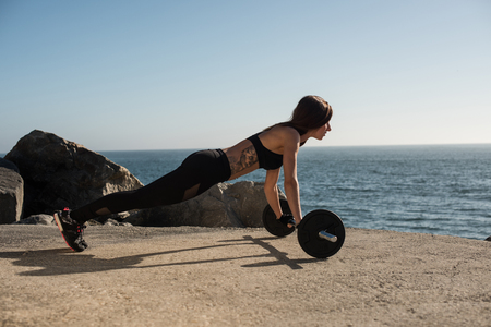 Fitness woman with tattoos lifting weights - Outdoorの写真素材