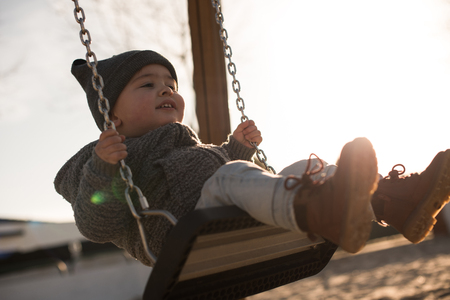 Toddler having fun on a swing seat - Sunset Lightの写真素材