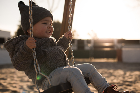 Toddler having fun on a swing seat - Sunset Lightの写真素材