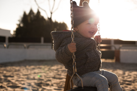 Toddler having fun on a swing seat - Sunset Lightの写真素材