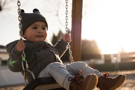 Toddler having fun on a swing seat - Sunset Lightの写真素材