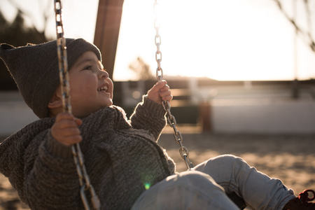 Toddler having fun on a swing seat - Sunset Lightの写真素材