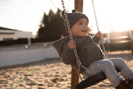 Toddler having fun on a swing seat - Sunset Lightの写真素材
