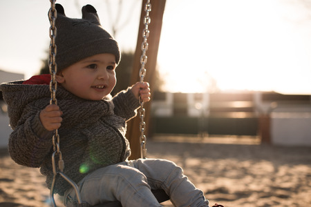 Toddler having fun on a swing seat - Sunset Lightの写真素材