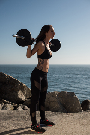 Fitness woman with tattoos lifting weights - Outdoorの写真素材