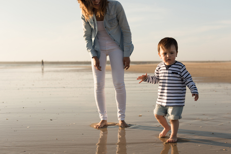 Young mother exploring the beach with toddlerの写真素材