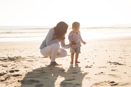 Young mother exploring the beach with her babyの写真素材