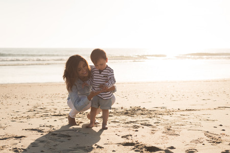 Young mother exploring the beach with her babyの写真素材