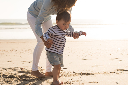 Young mother exploring the beach with her babyの写真素材