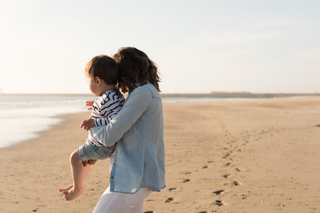 Young mother exploring the beach with toddlerの写真素材
