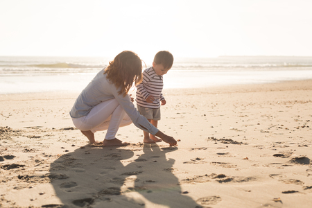 Young mother exploring the beach with toddlerの写真素材
