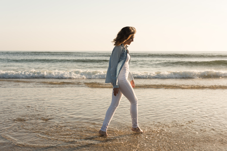 Beautiful woman enjoying sunset at the beachの写真素材