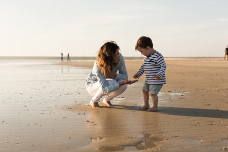 Young mother exploring the beach with toddlerの写真素材