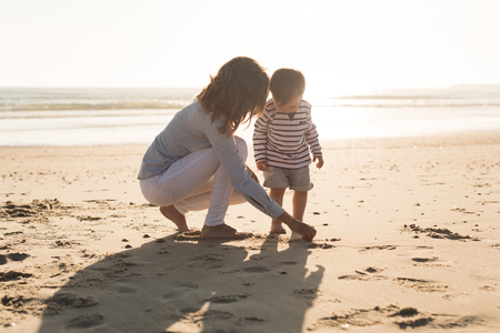 Young mother exploring the beach with toddlerの写真素材