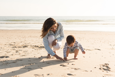 Young mother exploring the beach with toddlerの写真素材