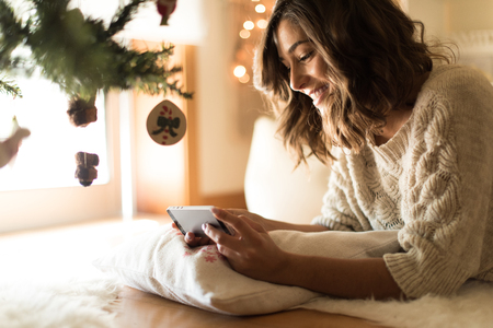 Woman using a smartphone at home - Winter and Christmas Seasonの写真素材