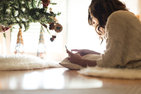 Woman using a smartphone at home - Winter and Christmas Seasonの写真素材