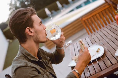 Man drinking cocktail and lunching near the poolの写真素材