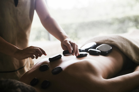 Man having a back massage with oil and hot stonesの写真素材