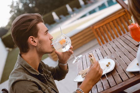 Man drinking cocktail and lunching near the poolの写真素材