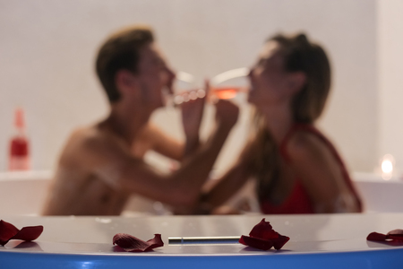 Romantic young couple drinking champagne in hot tubの写真素材