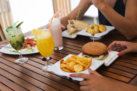 Couple lunching salad and hamburgers and drinking natural juicesの写真素材