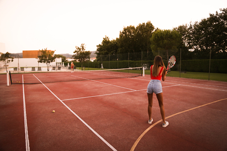 Couple playing tennis at the court - Natural sunset lightの写真素材