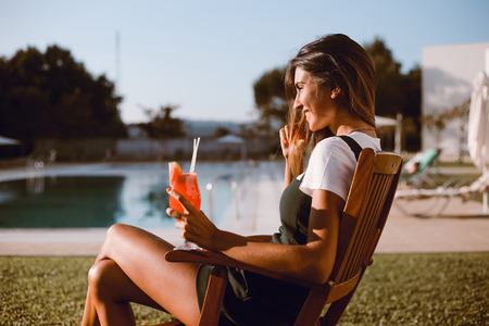 Beautiful woman drinking cocktail near the pool - Spring and Summerの写真素材
