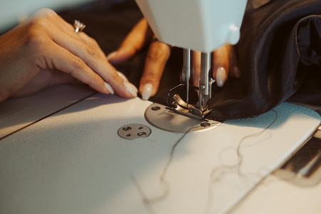 Close up of hands. Woman tailor working on sewing machine.の写真素材