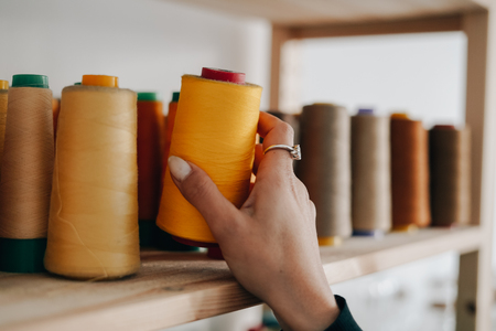 Tailor woman choosing colorful thread for sewing machineの写真素材