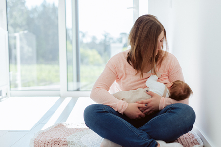 Young Mother breastfeeding newborn baby at homeの写真素材