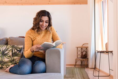 Woman At Home Lying On Reading Book on sofaの写真素材