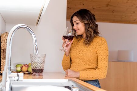 Woman drinking a glass of wine in a modern kitchen