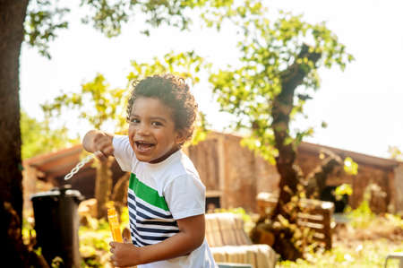 Happy african little boy playing with soap bubbles in natureの写真素材
