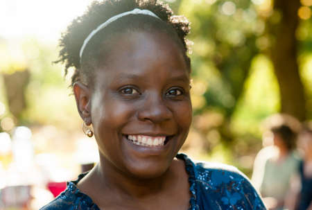 Portrait of a natural beautiful african woman smiling at the camera in nature.