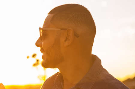 Happy latin man walking and enjoying the sunset with a natural landscape view. Warm natural light.の写真素材