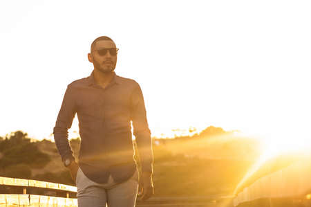 Happy latin man walking and enjoying the sunset with a natural landscape view. Warm natural light.の写真素材