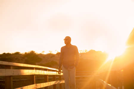 Happy latin man walking and enjoying the sunset with a natural landscape view. Warm natural light.
