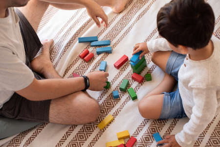 Little kid and his father playing at home with wood building blocks. Homeschooling. Stay at home. Family timeの写真素材