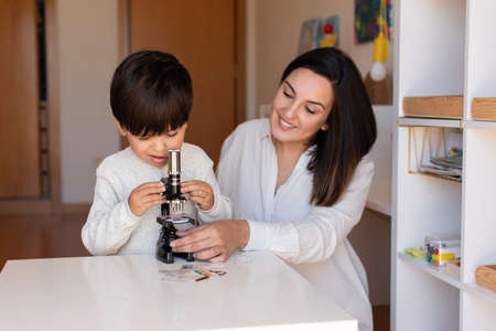 Lillte Kid exploring science with a microscope and mother or teacher help. Homeshooling. Learning Community. Montessori Schoolの写真素材