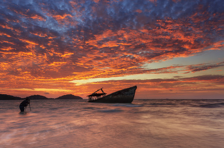 fiery sky over a wrecked boatの写真素材