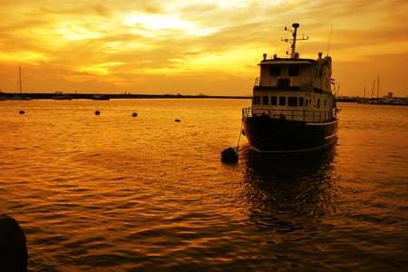  Boat on calm water with golden reflection and skies at the background.のeditorial素材