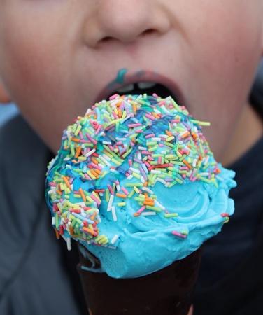 Boy eating a blue ice cream with sauce on his lipsの素材