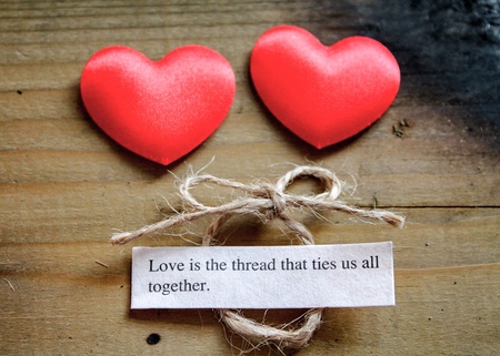 Two silky love hearts next to a loving quote and a tied bowの素材