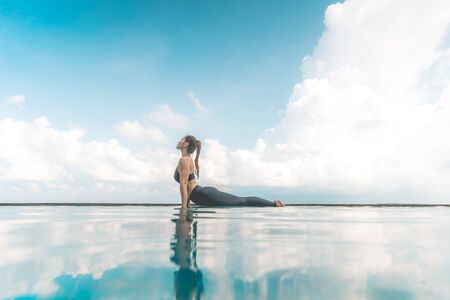 Vacation of Attractive Asian woman practice Cobra Pose on the pool above the beach in the morning with beautiful sea in Tropical island,Feeling comfortable and relax in holiday,Vacations Conceptの写真素材