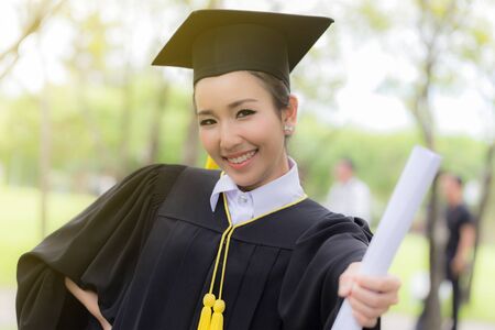 Attractive Beautiful Asian Graduated woman in cap and gown smile with certificated feeling so proud and happiness in success graduated day,Education Success Conceptの写真素材