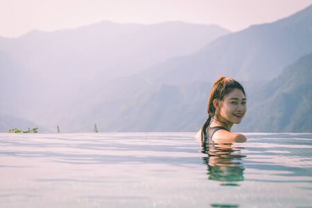 Vacations of Woman relax in tropical infinity pool above the Mountain peak in the morning in front of beautiful nature views in SAPA vietnam,Feel so Happiness and comfortable in holidaysの写真素材